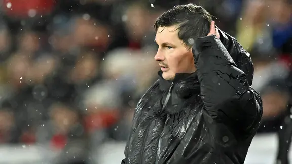 HSV-Trainer Merlin Polzin steht im Regen und hat eine Hand im Haar.
