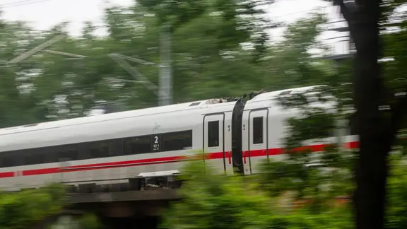 Ein ICE der Deutschen Bahn fährt schnell durch ein bewaldetes Gebiet. | picture alliance/dpa | Fernando Gutierrez-Juarez Ein ICE der Deutschen Bahn fährt schnell durch ein bewaldetes Gebiet.