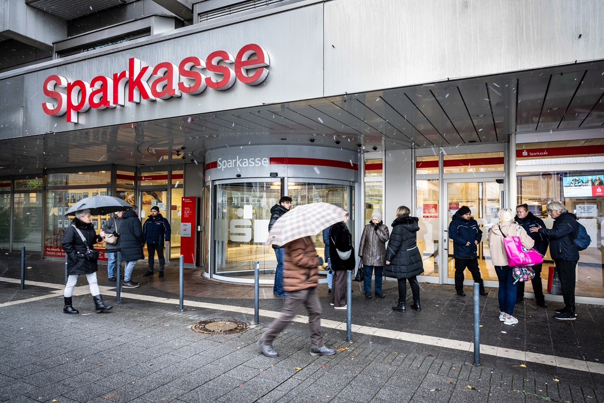Mehrere Personen befinden sich vor einer Sparkasse-Filiale.