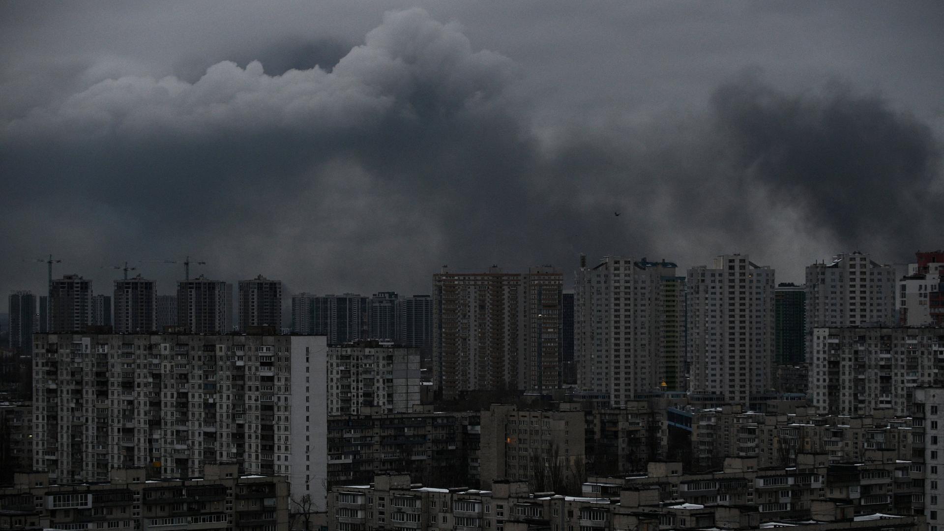 Es ist sehr düster. Über Wohnhäusern steigt Rauch auf. Es ist sehr düster. Über Wohnhäusern steigt Rauch auf.
