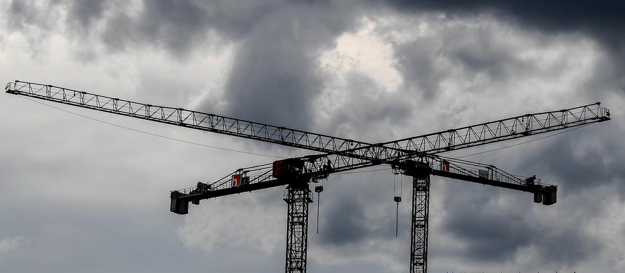Baukräne sind vor dunklen Wolken zu sehen.