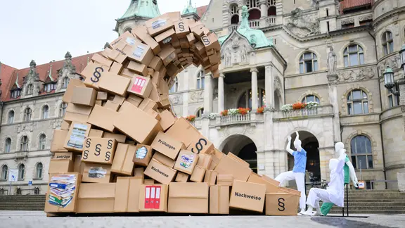 Eine "Bürokratie-Welle" aus Kartons, Aktenordnern, Formularen und Gesetzestexten steht als Symbol für den Bürokratieaufwand im Gesundheitswesen vor dem Neuen Rathaus. | Julian Stratenschulte/dpa Eine "Bürokratie-Welle" aus Kartons, Aktenordnern, Formularen und Gesetzestexten steht als Symbol für den Bürokratieaufwand im Gesundheitswesen vor dem Neuen Rathaus.