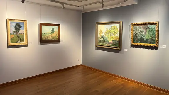 Bilder hängen in einer Ausstellung an der Wand