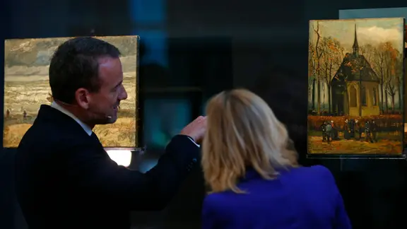 er Direktor des Van Gogh Museums, Axel Rüger, und die niederländische Kulturministerin Jet Bussemaker betrachten am 21.03.2017 in Amsterdam (Niederlande) die einst gestohlenen und nun wieder aufgetauchten Gemälde «Zeegezicht bij Scheveningen» (Meeressicht bei Scheveningen, 1882) und «Het uitgaan van de Hervormde Kerk te Nuenen» (Die Kirche von Nuenen mit Kirchgängern, 1884/1885) | picture alliance / Peter Dejong/AP/dpa | Peter Dejong er Direktor des Van Gogh Museums, Axel Rüger, und die niederländische Kulturministerin Jet Bussemaker betrachten am 21.03.2017 in Amsterdam (Niederlande) die einst gestohlenen und nun wieder aufgetauchten Gemälde «Zeegezicht bij Scheveningen» (Meeressicht bei Scheveningen, 1882) und «Het uitgaan van de Hervormde Kerk te Nuenen» (Die Kirche von Nuenen mit Kirchgängern, 1884/1885)
