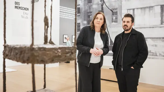 Dem spektakulären Fall um Giacometti-Fälschungen haben sich Lenore Lötsch und Torben Steenbuck im Podcast Kunstverbrechen gewidmet. | Melanka Helms Lenore Lötsch und Torben Steenbuck stehen vor einer Giacometti-Skulptur