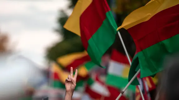 Vor mehreren Flaggen Kurdistans zeigt eine Person das Victoryzeichen bei einer Demonstration in Duisburg. | dpa - Bildfunk, Fabian Strauch Vor mehreren Flaggen Kurdistans zeigt eine Person das Victoryzeichen bei einer Demonstration in Duisburg.
