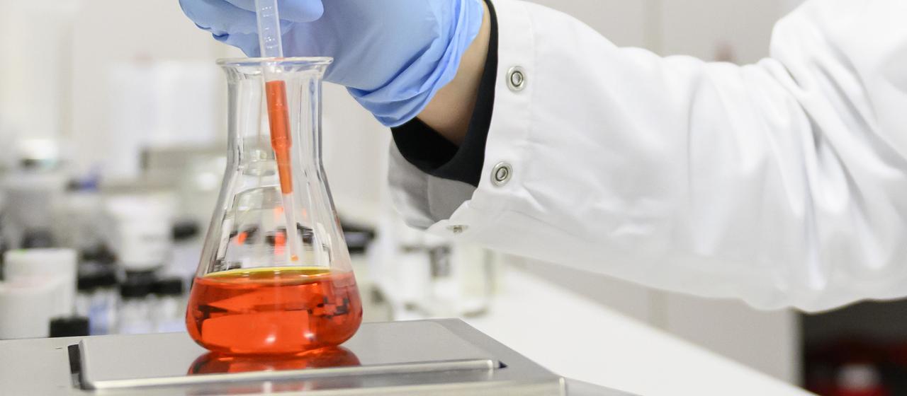 Eine Person arbeitet in einem Labor mit einem Reagenzglas