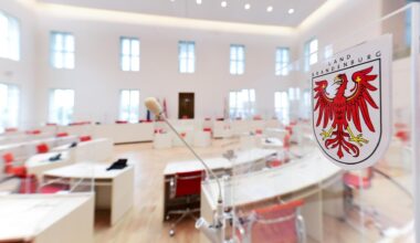Blick in den Brandenburger Landtag. Weiße, in einem Rund angeordnete Tische sind zu sehen. Rote Sessel stehen an den Tischen.