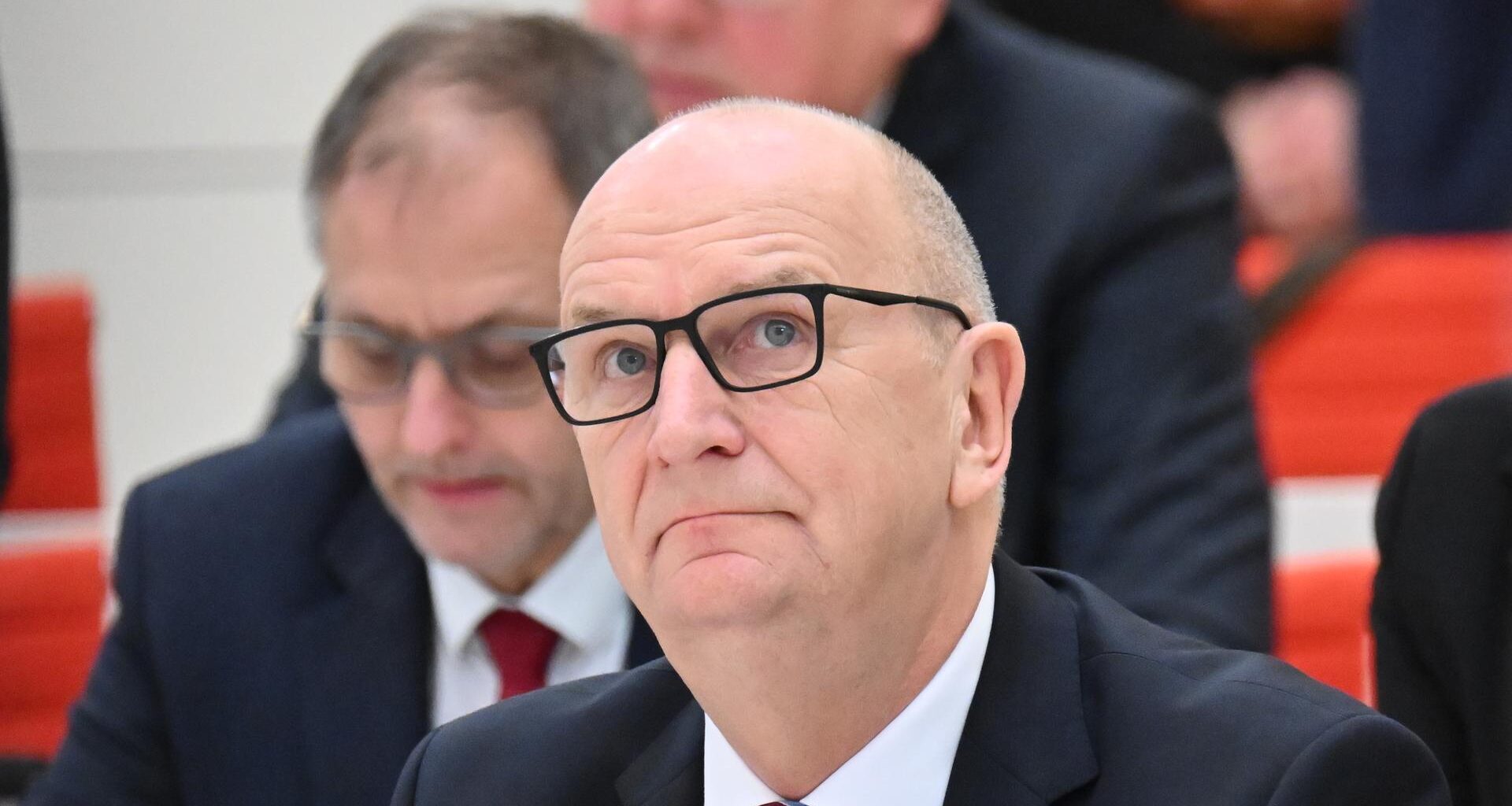 Woidke mit ernstem Blick bei einer Plenarsitzung im Brandenburger Landtag, dahinter weitere Abgeordnete.