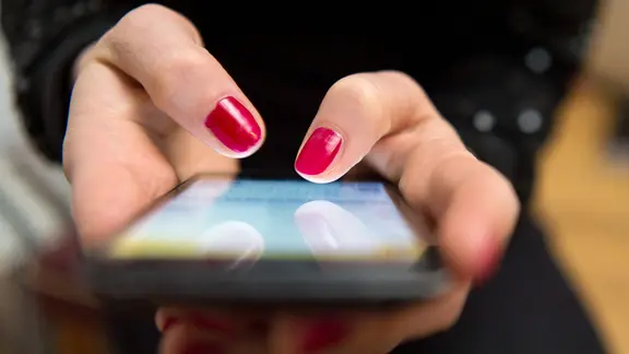 Eine Frau tippt auf einem Smartphone.