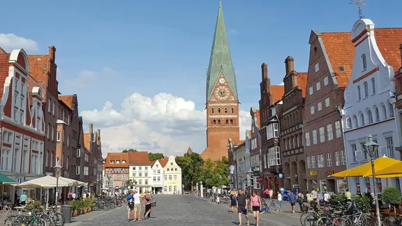 Die St.-Johannis-Kirche in Lüneburg, im Vordergrund histsorische Giebelhäuser am Sande