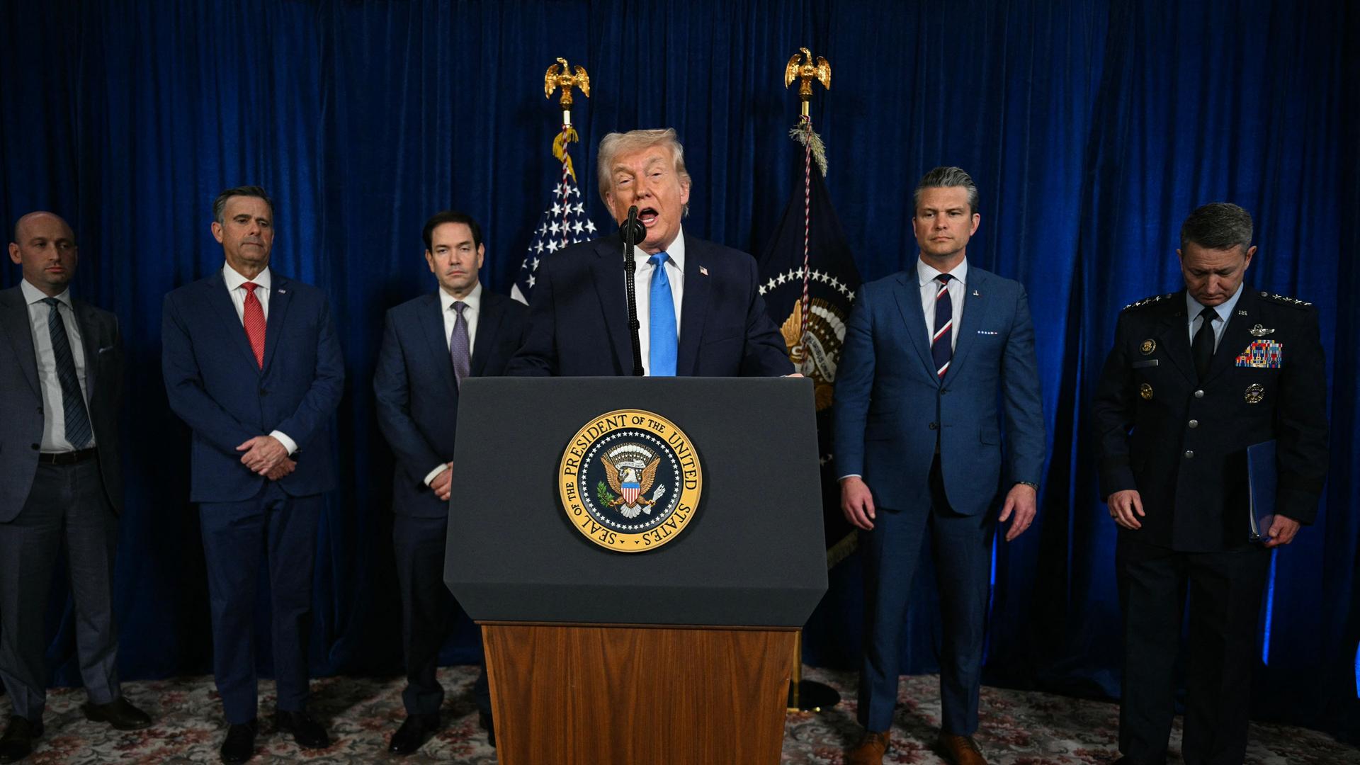 Trump spricht hinter einem Rednerpult. Hinter ihm stehen Mitglieder der US-Regierung.