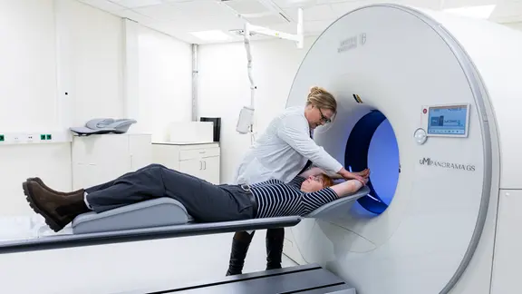 Eine Frau wird darauf vorbereitet in eine große Röhre in einem Krankenhaus eingelassen zu werden.