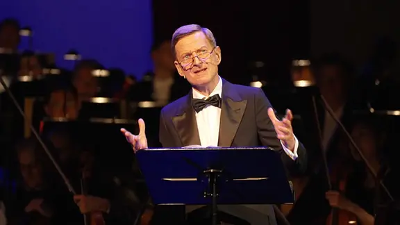 Michael Kessler steht am Rednerpult auf der Bühne