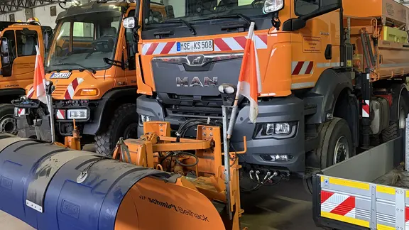 Orangene Räumfahrzeuge in einer Halle