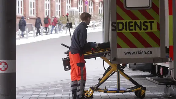 Ein Sanitäter lädt eine Trage in einen Rettungswagen.