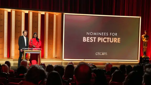 Ein Mann und eine Frau (Lewis Pullman und Danielle Brooks) präsentieren die Nominierungen der Oscar Academy - die Tafel zeigt "Best Picture" (bester Film) an, daneben steht eine Oscar-Replik