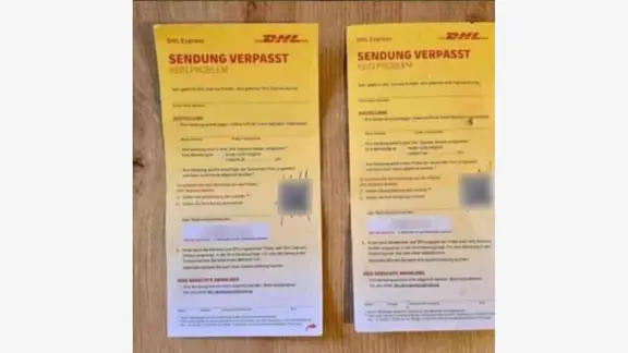 Auf einem Tisch liegen gefälschte Paketzettel von DHL mit QR-Code