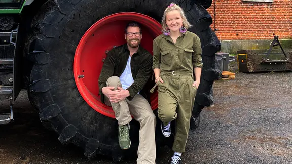 Landwirtin Maja Mogwitz und NDR Moderator Andreas Kuhlage sitzen in einem Treckereifen auf der Felge.