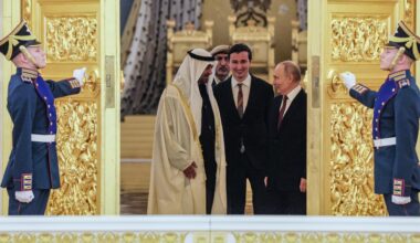 Der russische Präsident Putin und der Präsident der Vereinigten Arabischen Emirate, Scheich Mohamed bin Zayed Al Nahyan, stehen sich gegenüber und schauen sich an. Ihnen wird von zwei Soldaten eine goldbesetzte Tür aufgehalten.