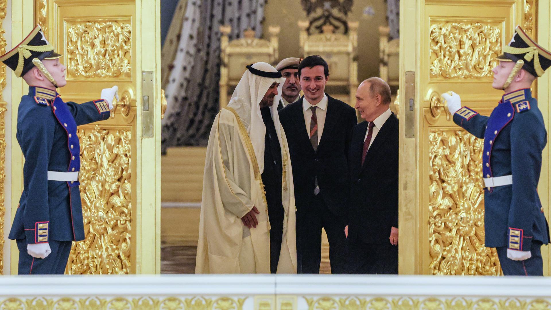 Der russische Präsident Putin und der Präsident der Vereinigten Arabischen Emirate, Scheich Mohamed bin Zayed Al Nahyan, stehen sich gegenüber und schauen sich an. Ihnen wird von zwei Soldaten eine goldbesetzte Tür aufgehalten. Der russische Präsident Putin und der Präsident der Vereinigten Arabischen Emirate, Scheich Mohamed bin Zayed Al Nahyan, stehen sich gegenüber und schauen sich an. Ihnen wird von zwei Soldaten eine goldbesetzte Tür aufgehalten.