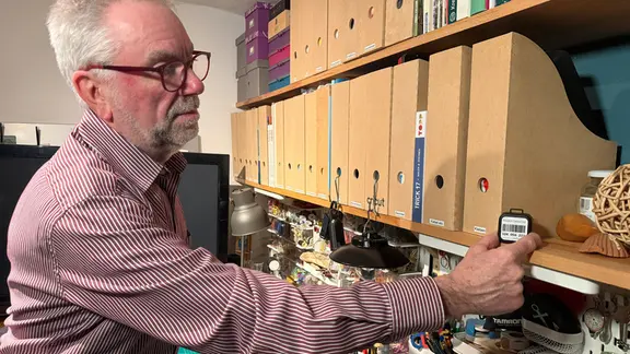 Ein Hausbesitzer stellt ein Radonmessgerät in ein Regal hin. | NDR / Jörn Zahlmann Ein Hausbesitzer stellt ein Radonmessgerät in ein Regal hin.