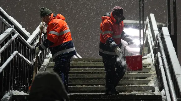 Mitarbeiter der Stadtreinigung streuen eine Treppe in Hamburg.