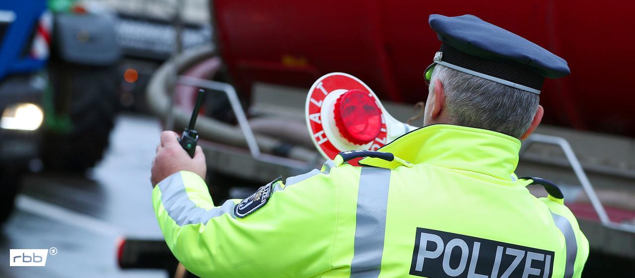 Ein Polizist in gelber Leuchtjacke bei einer Verkehrskontrolle. (Quelle: dpa/Maximilian Koch)