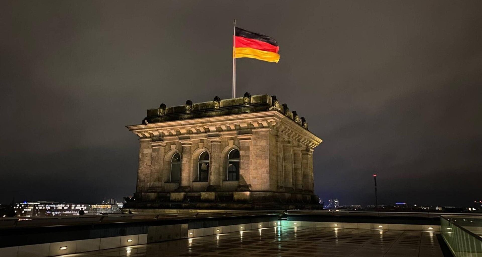 Die Deutschlandfahne auf dem Dach des Reichstages bei Nacht.