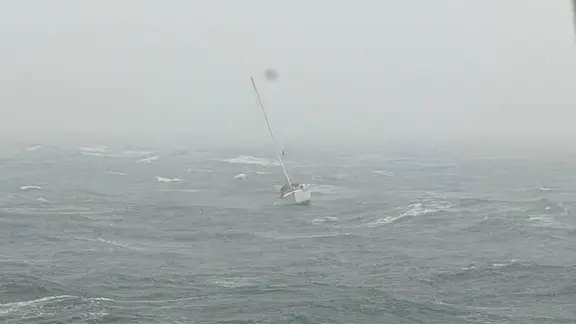 Ein Einhandsegler bei trübem, stürmischem Wetter auf dem Meer.