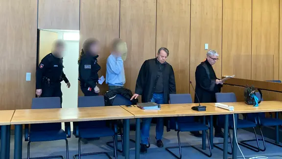 Ein Angeklagter in einem Prozess sitzt neben seinen Verteidigern in einem Saal des Landgerichts Hildesheim