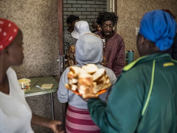 Displaced women from the informal settlement of Sporong by the ongoing unrest between the community and  a group of artisanal miners commonly referred to as "zama zamas", serve sandwiches from the communal kitchen at the Randgate Community Hall in Randfontein, on January 22, 2026 where the displaced took refuge. Residents and local officials blame artisanal miners, long associated with sudden eruptions of violence, running gun battles and the shadowy networks that sustain South Africa's illicit gold trade. 
Known locally as "zama zamas" -- "those who try" in the Zulu language -- they have become an entrenched presence in the shantytowns that ring Johannesburg and its satellite settlements along the gold reef. (Photo by MARCO LONGARI / AFP)