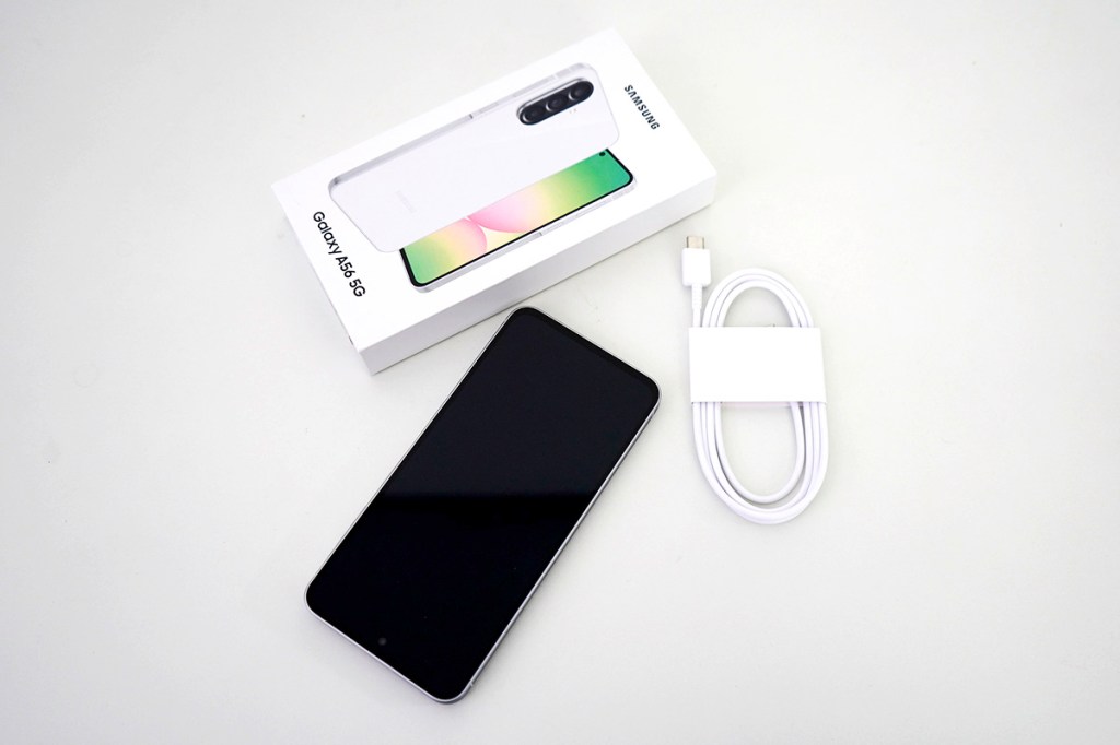 Das Samsung Galaxy A56 5G liegt neben der Verpackung und dem mitgelieferten Ladekabel auf einem weißen Tisch.