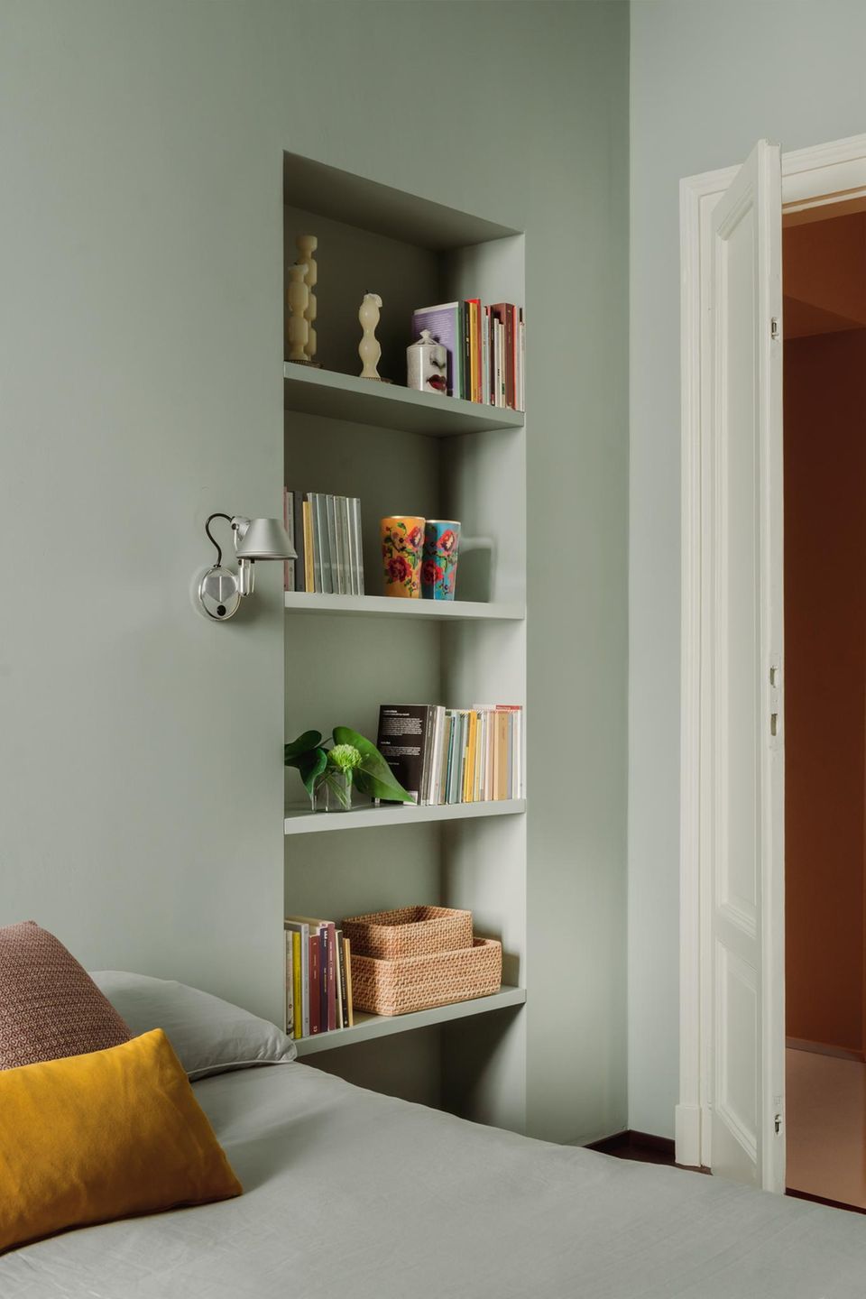 Schlafzimmer im Anschnitt mit grüner Wand und einer Wandnische mit Deko