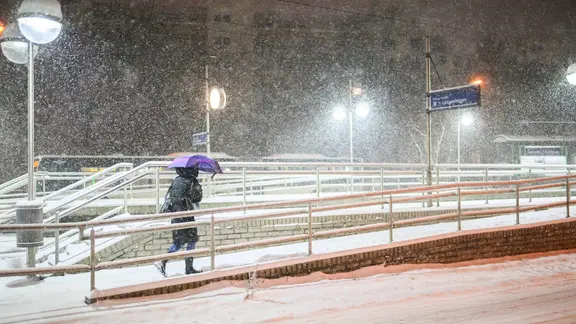 Eine Frau geht mit Schirm durchs Schneetreiben zu einer Straßenbahnstation in Hannover | Julian Stratenschulte/dpa Eine Frau geht mit Schirm durchs Schneetreiben zu einer Straßenbahnstation in Hannover