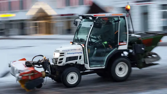 Ein Winterdienst-Fahrzeug mit der Aufschrift «Gehwegreinigung» streut in der Innenstadt, um glatten Straßen vorzubeugen.