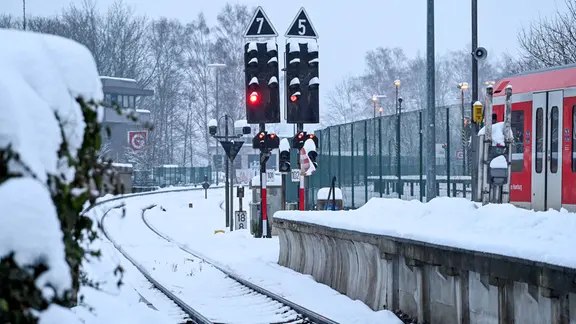 Eine S-Bahn der Linie S1 steht im verschneiten Bahnhof von Wedel. 