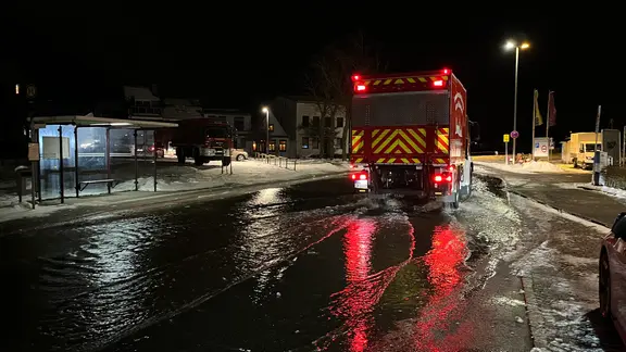 Ein Feuerwehrfahrzeug fährt auf einer überfluteten Straße