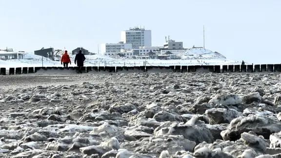 Spaziergänger sind am Strand unterwegs. | dpa, Volker Bartels Spaziergänger sind am Strand unterwegs.
