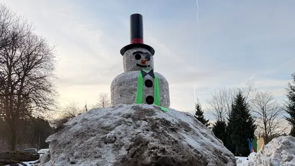 Ein riesiger Schneemann mit einem sehr hohen Zylinder, Gesicht, Fliege und langem grünem Schal | NDR, Lydia Callies Ein riesiger Schneemann mit einem sehr hohen Zylinder, Gesicht, Fliege und langem grünem Schal