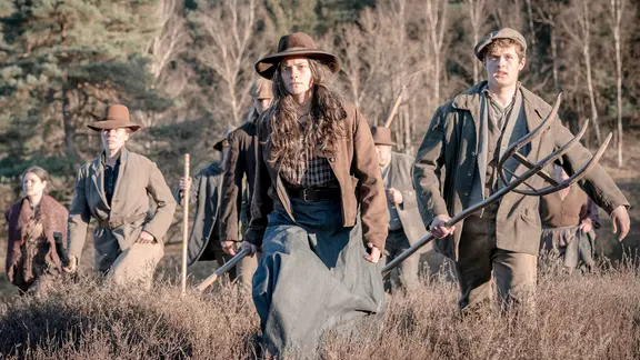 Eine Gruppe von bewaffneten Menschen in Kleidung des 19. Jhds. laufen über ein Feld | NDR Eine Gruppe von bewaffneten Menschen in Kleidung des 19. Jhds. laufen über ein Feld