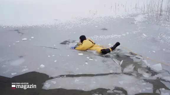 Eine Person in Schutzkleidung auf einer eingebrochenen Eisfläche.