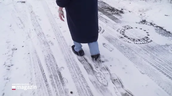 Eine Person läuft mit Anti-Rutsch-Schuhüberzügen auf einer vereisten Straße.