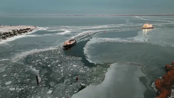 Eine Fähre fährt durch eine Schneise in Eis auf dem Meer.