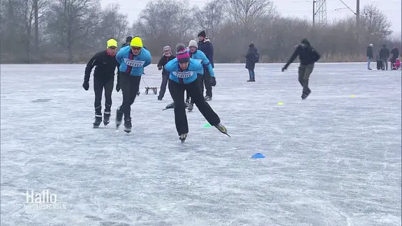 Mehrere Schlittschuhläufer laufen auf dem Eis. | Screenshot Mehrere Schlittschuhläufer laufen auf dem Eis.