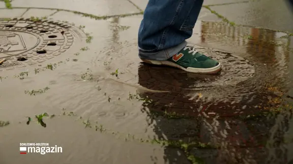 Ein Fuß geht durch eine Pfütze