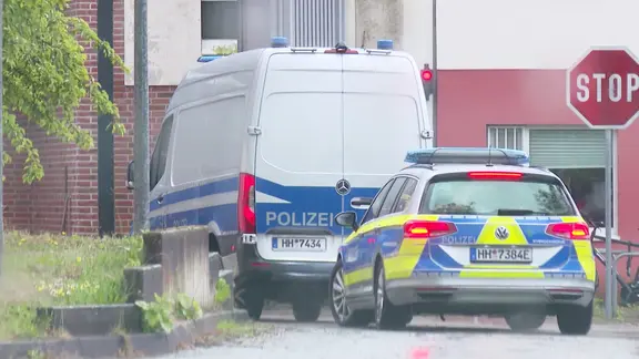 Zwei Polizeifahrzeuge fahren auf ein Grundstück.