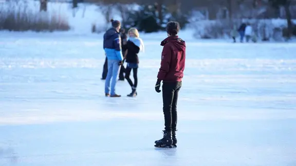 Menschen stehen auf einem zugefrorenen See.