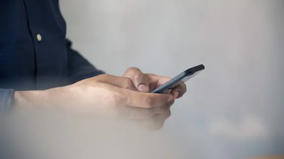 Ein Mann tippt auf seinem Smartphone herum.