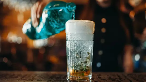 Sprudelwasser wird aus einer Flasche in ein Glar gegossen.